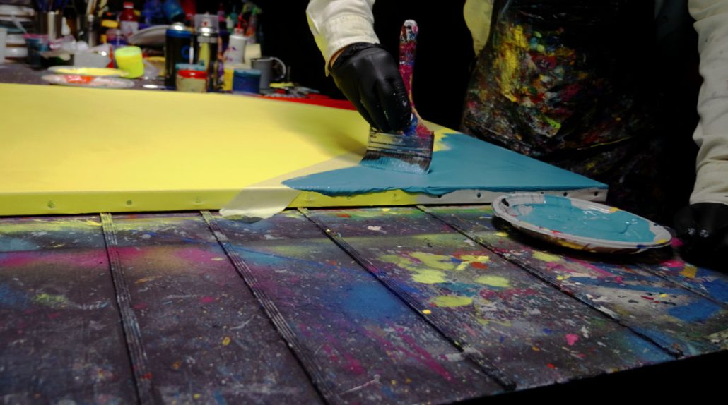 Adding red and turquoise triangular shapes using masking tape to define the background