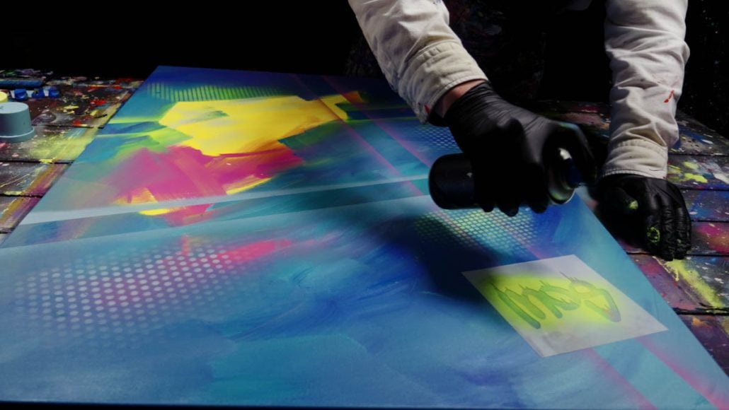Applying spray paint with a stencil to structure the background of the artwork Art is My Revolt